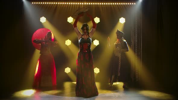 Girls Dance in Sexy Theatrical Costumes. Young Hot Brunettes with Long Hair. Bright Makeup and Red alt