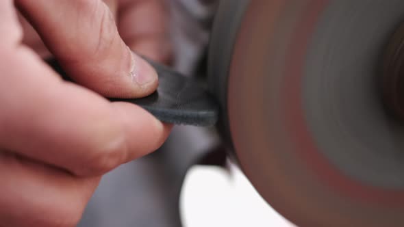 The Craftsman Is Sharpening the Edges of a Belt on a Special Machine alt