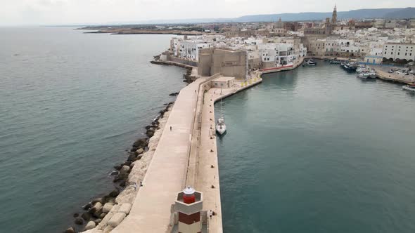 Aerial drone shot pushing from a lighthouse to a castle wall. Monopoli, Italy alt