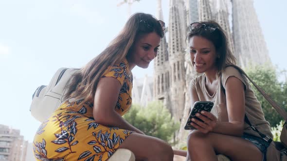 Female tourists using smarphone at Sagrada Familia, Barcelona, Spain alt