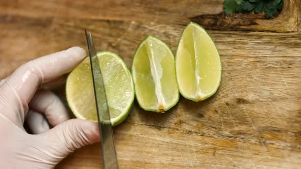 Arms of barkeeper add fresh juice in transparent glass with greenery mint and slices lime close-up alt