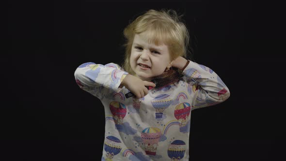 Little Baby Girl in Pajama with Funny Headdress Is Combing alt
