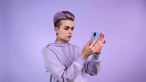 Young Woman in Purple Reading Shocking News at Internet Grabbing Head alt