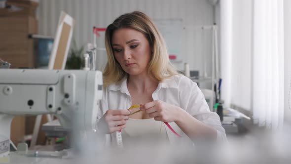 Young Beautiful Light Hair Seamstress Gets Bad News By Smartphone in the Workplace