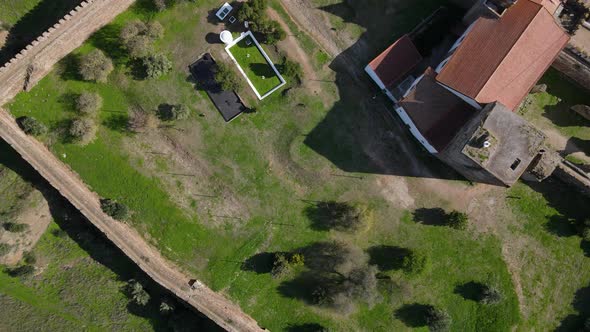Mourao castle defensive walls and church, Portugal. Aerial top-down rising alt