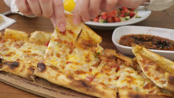 Woman Is Taking a Slice of Khachapuri From Wooden Board To Eat, Hands Closeup. alt