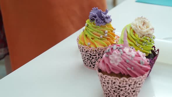 Four nicely decorated colorful muffins. Pastry cook puts cupcake on the table. 