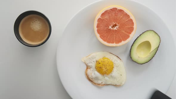 Simple Breakfast with Sunny Side Up Egg Being Added on the White Plate alt
