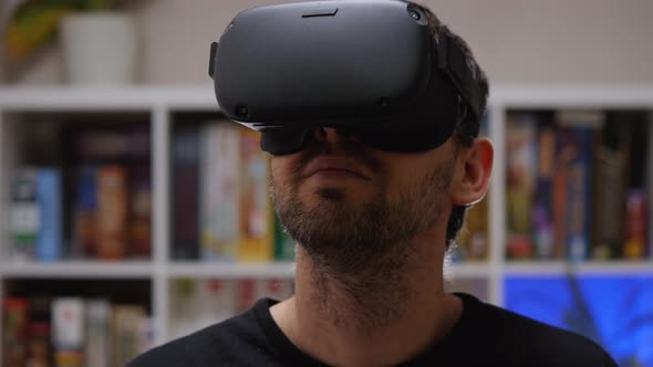Close-up of a bearded man wearing VR glasses on his head. Home interior alt