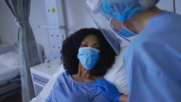 Diverse female doctor and patient wearing face masks during heart examination alt