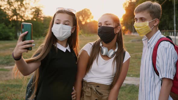 Three Schoolchildren in Protective Masks Take a Selfie alt