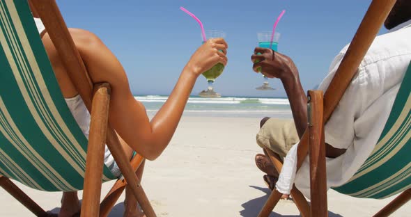 Couple toasting glasses of cocktails at beach 4k alt