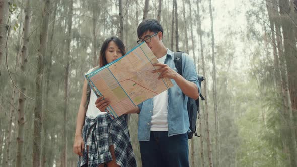 Asian hiker couple trekking in forest. Young happy backpack male and female walking.