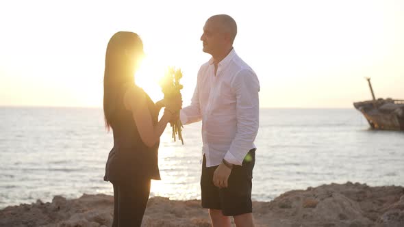 Side View of Loving Man Giving Bouquet of Yellow Tulips to Woman Kissing Pregnant Spouse in Slow alt