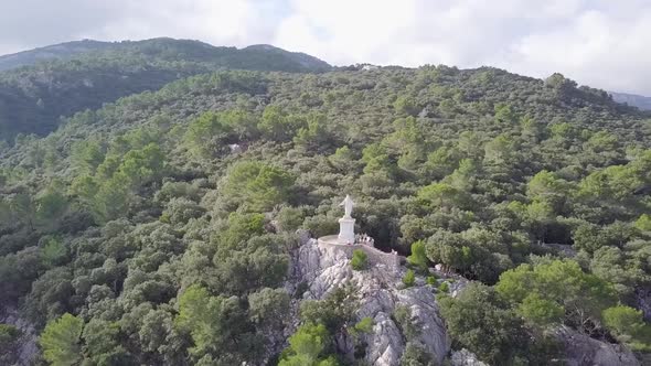 Aerial view of Sagrado corazón de Jesús statue on a mountain with green forest. alt