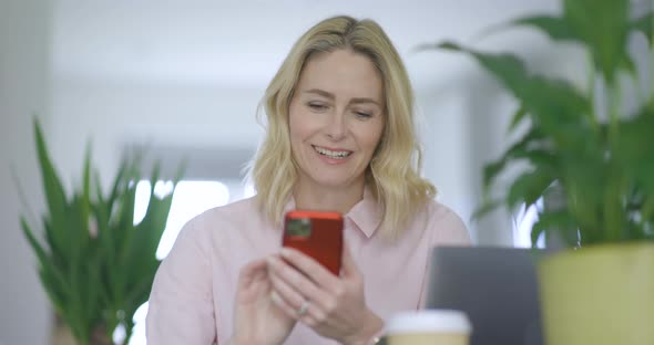 Smiling woman text messaging on smartphone