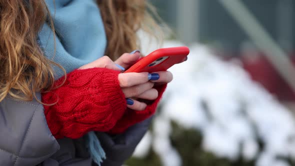 Close up of Woman Hands Texting on Smartphone Standing on Street in Winter City on New Year