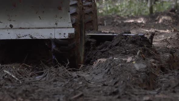 Slow Motion of Road Leveling Motor Grader on Bad Forest Road at Work. Excavator Scraping Dirt Making alt