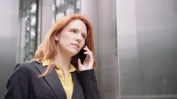 Businesswoman in city using smart phone with takeaway coffee