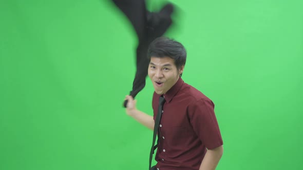 Crazy, funny happy Asian business man employee putting his black suit on his shoulder. alt
