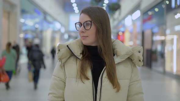 Young Woman Standing and Looking at Camera in Shopping Mall or Trade Center