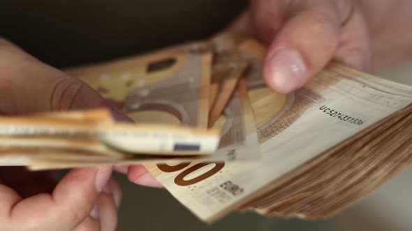 Man Counting Money. Close up of male hands counting big pile of 50 euro banknotes. Concept of high