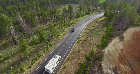 Drone camera takes off from a height a traveling white trailer in the canyon (Zion National Park) alt
