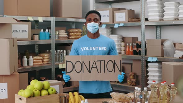 African American Man in Face Mask and Gloves Holding Donation Banner alt