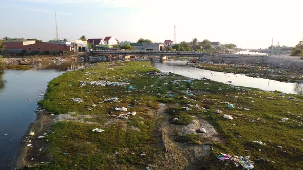 Scene with garbage on bank of polluted river, Vietnam. Aerial flying forward alt