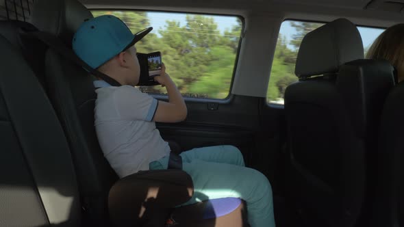 Boy taking pictures with cell when traveling by car alt