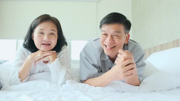 happiness wellness healthy old senior asian couple smile laugh together enjoy laydown casual in bed alt