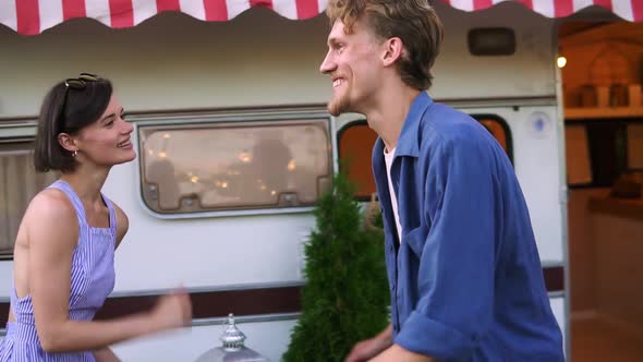Smiling Couple Man and Woman Having Fun Time Together Dancing Together Near House on Wheels Outdoors alt