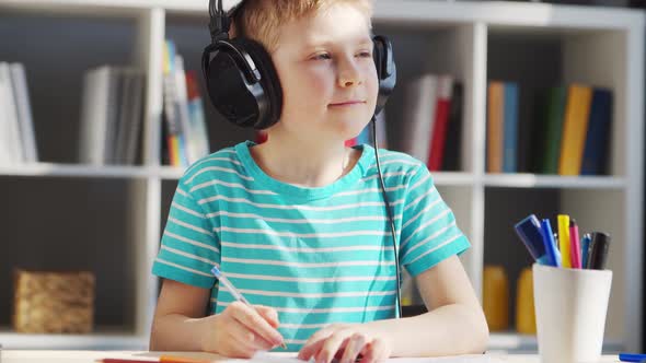 Boy is Doing  Homework at the Table. Cute Child is Learning at Home. alt
