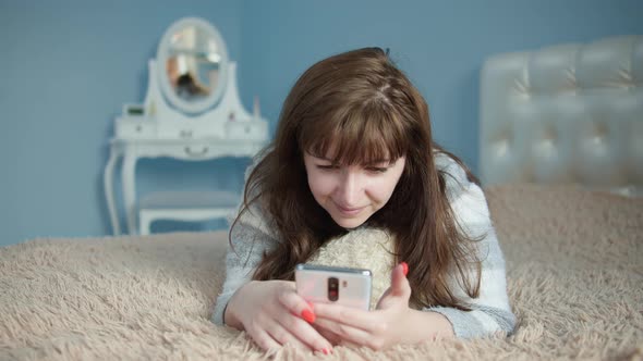 Pretty Woman Lies on the Bed Chatting on the Phone and Dreaming