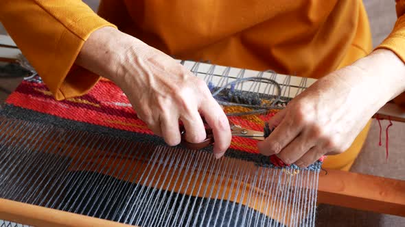 Artisan is weaving and cutting the ends of the threads to create a cut pile carpet effect