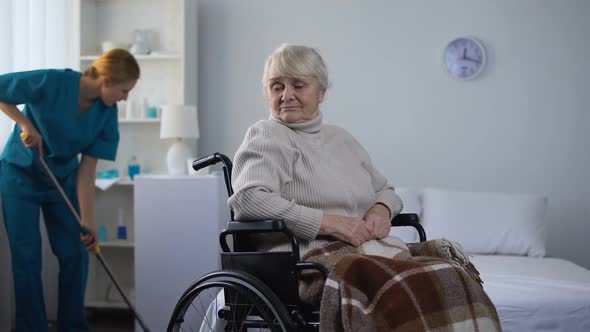 Sad Woman in Wheelchair Watching Hospital Janitor Cleaning Room, Medical Center alt