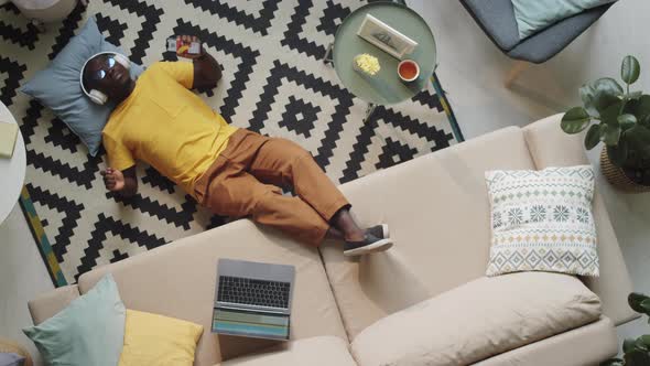 Black Man in Headphones Enjoying Music while Lying on Floor alt