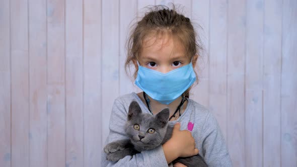 Child in Medical Mask with Cat in Hands During Coronavirus Pandemic. Careful Patient Care Concept alt