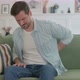 Young Man Having Back Pain While Sitting on Sofa