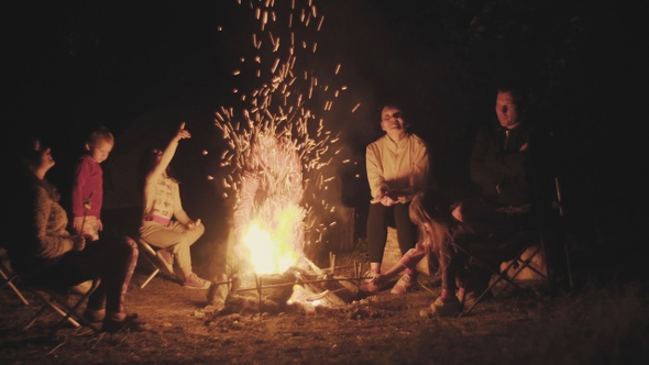Family on a picnic near a campfire in the dark