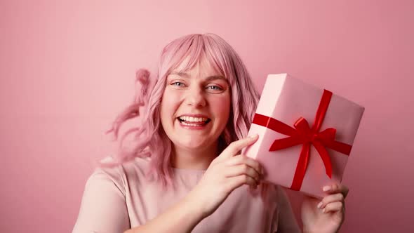 Happy Young Pink Hair 30s Caucasian Woman in Good Mood Holding Present Gift Box with Red Ribbon Bow