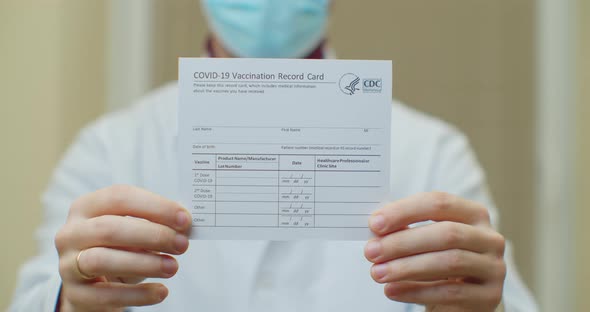 Doctor Is Holding a Vaccination Record Card alt