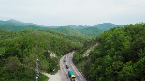 Aerial Fly Over Caucasian Mountains and Winding Road with Cars alt
