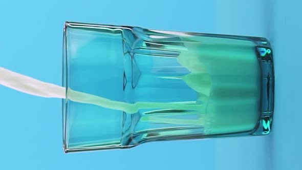 Vertical Video Slow Motion Closeup Shot of Milk Cold Beverage Drink Pooring Into Blue Faceted Glass