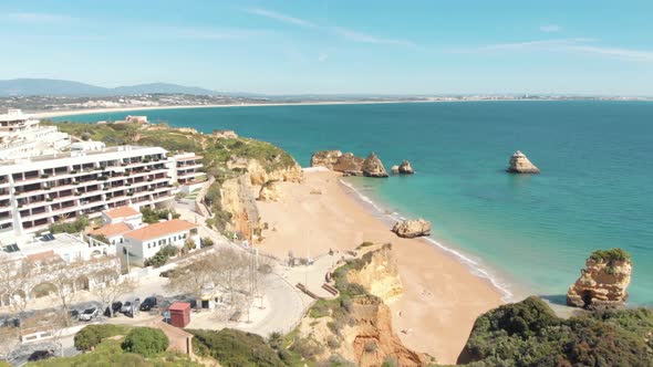 View over green hill shrouding golden Dona Ana beach, Lagos, Algarve, Portugal alt