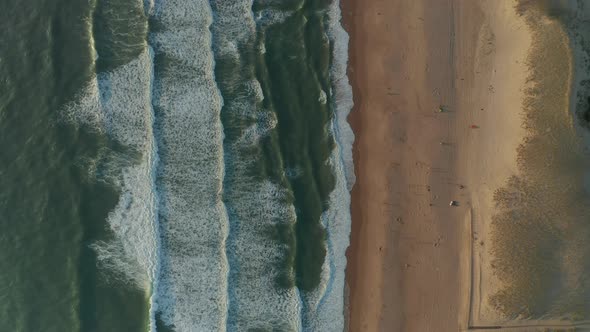 Beach with Sand Dunes and Blue Ocean Waves Crashing Against Shore Line, Aerial Birds Eye Top Shot alt