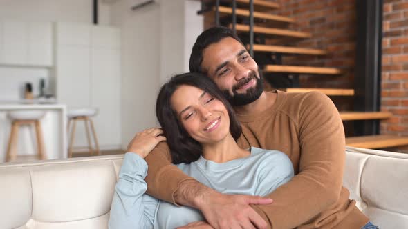 Happy Indian Newlyweds Moved in New Apartment Sitting at the Sofa in Embrace