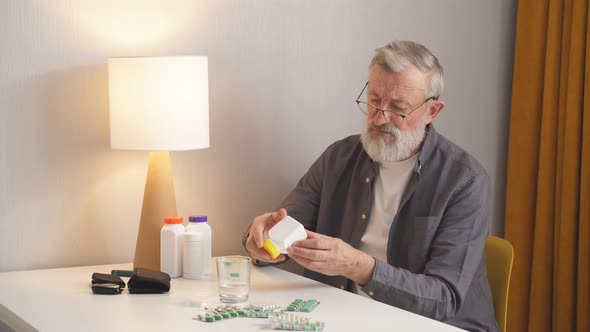 Portrait of an Elderly Man at the Table Choosing Pills
