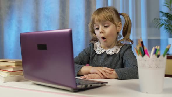 Child Schoolgirl Learning Lessons Distance Education at Home Sitting at Table Using Laptop Computer alt