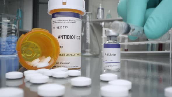Antibiotic pills and vaccine vial in medical lab with syringe placed alt